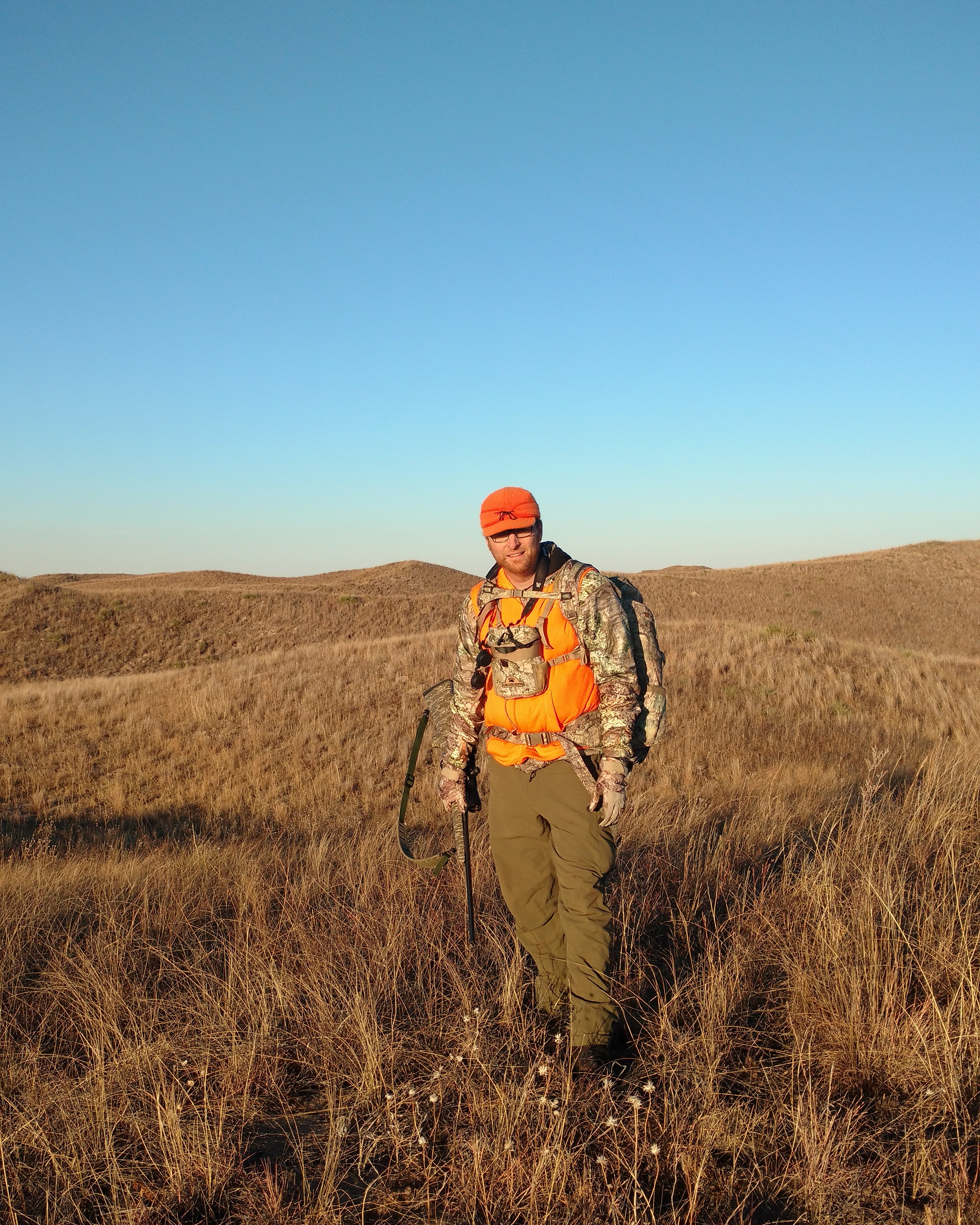 Todd Waldron standing in tall prairie grass at golden hour
